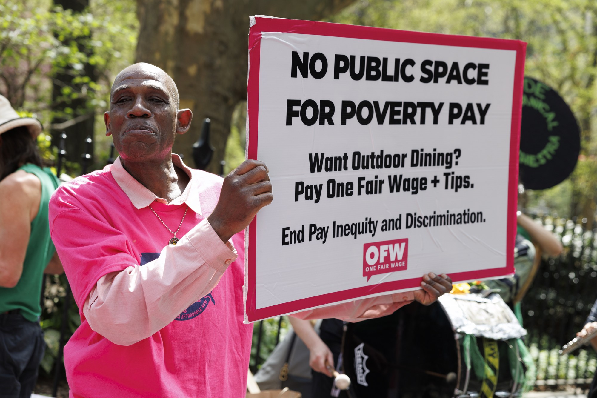 OFW member holds a placard reading &lsquo;NO PUBLIC SPACE FOR POVERTY PAY&rsquo; at the NYC City Hall action against outdoor dining subsidies, April 16, 2026